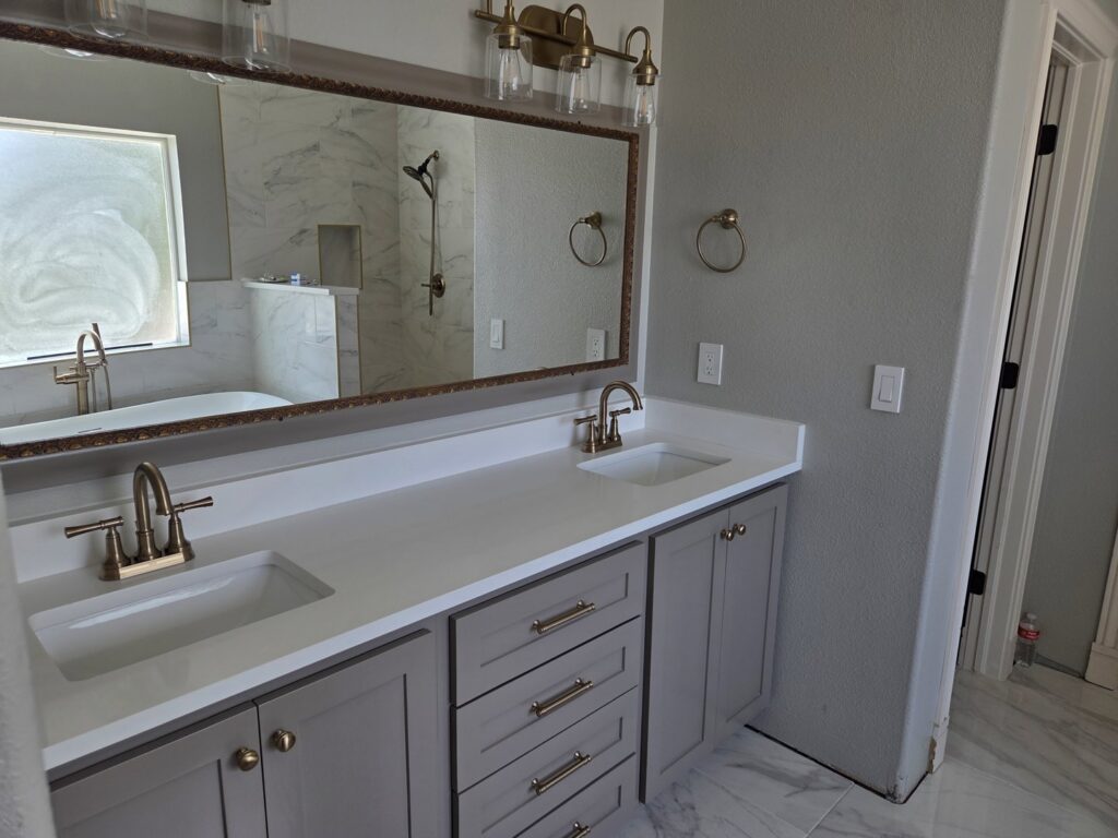 Modern bathroom vanity with dual sinks and elegant gold fixtures by APJ Construction Inc. in El Paso, TX.