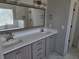 Modern bathroom vanity with dual sinks and elegant gold fixtures by APJ Construction Inc. in El Paso, TX.