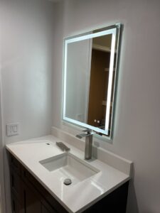 A modern bathroom vanity with a sleek sink and an illuminated mirror installed by Guzmanremodeling LlC in Renton, WA.