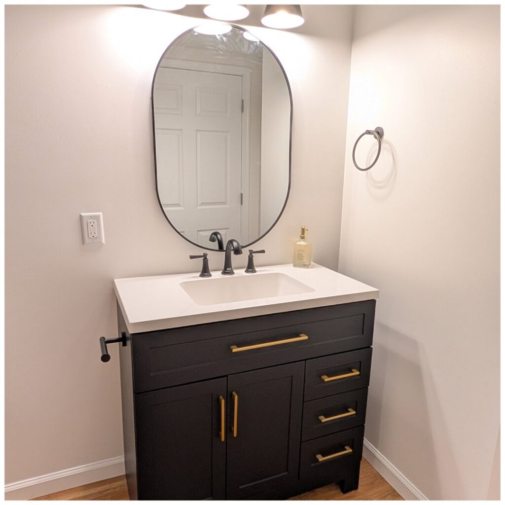 Modern bathroom vanity installation with black cabinet and gold hardware by Adam's Handyman and Contracting in Lancaster, PA.