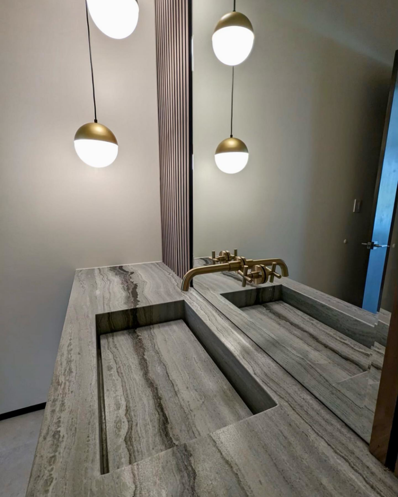 A modern bathroom featuring a double stone vanity with integrated sinks and brass faucets, installed by Dorado Stone Inc. in Tucson, AZ.