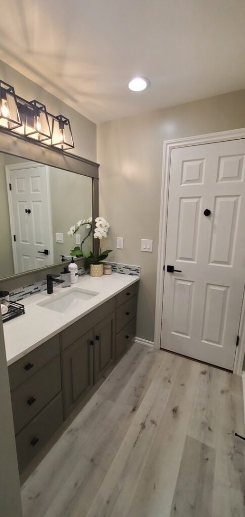 Modern bathroom vanity with dark gray cabinets, white countertop, and black fixtures, installed by Fisher Construction, LLC in Selah, WA.