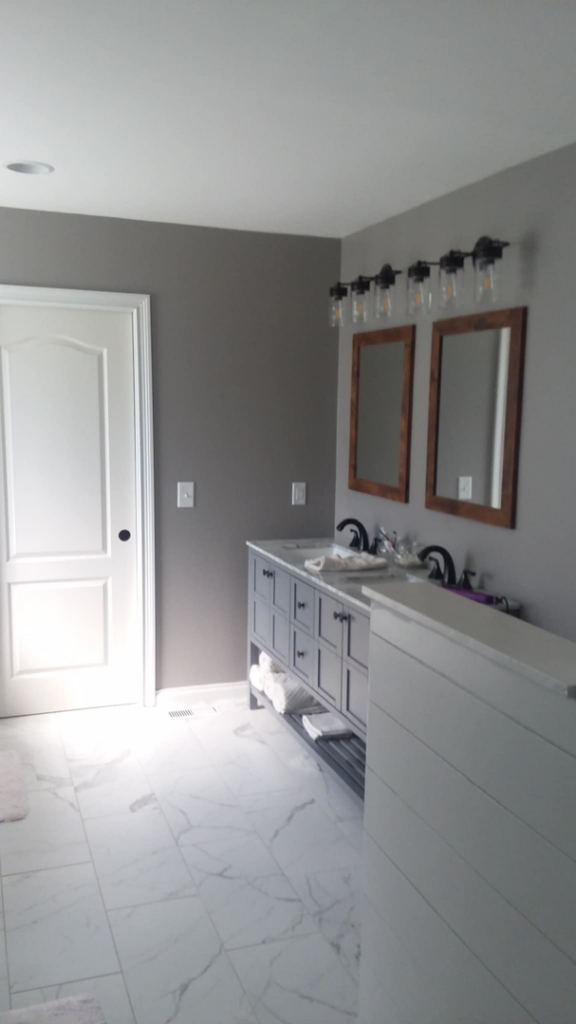 A newly remodeled modern bathroom featuring a double vanity and new flooring by Heritage Design & Remodel in Raleigh, NC.