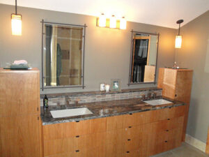 A modern bathroom vanity remodel with wood cabinets, granite countertops, and dual sinks by Hibbard Home Improvement in Williamsville, NY.