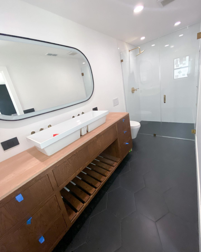 A modern bathroom featuring a long vanity and walk-in shower with black hexagonal tiles by Clean Cut Tile LLC in St. Louis, MO.