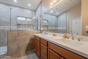A modern bathroom featuring a walk-in shower and double vanity, completed by Centennial Builders, LLC in Litchfield Park, AZ.