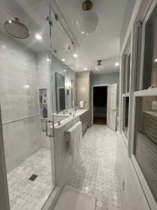 A modern bathroom remodel featuring a spacious walk-in shower, double vanity, and stylish tile work by Pro Finishes NC, LLC in Raleigh, NC.