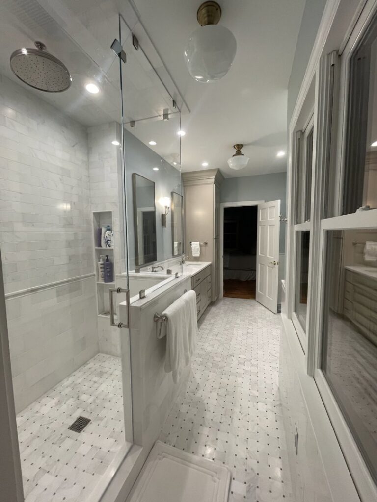 A modern bathroom remodel featuring a spacious walk-in shower, double vanity, and stylish tile work by Pro Finishes NC, LLC in Raleigh, NC.