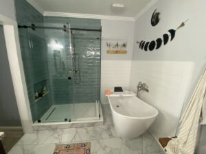 A modern bathroom featuring a large walk-in shower with glass doors and a freestanding tub by Stonehedge Construction in Buford, GA