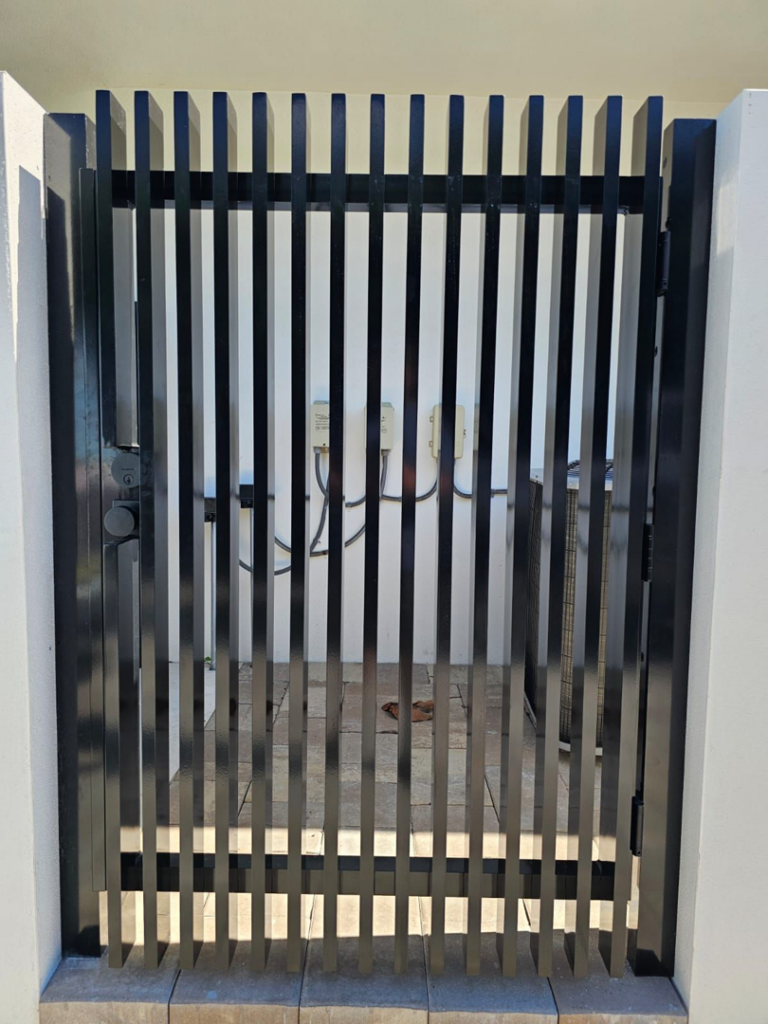 A modern black vertical slat gate installed by Aluminum Fence Contractor, Inc. in Hialeah, FL.