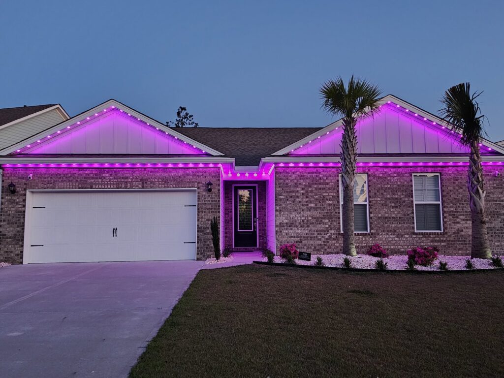 A modern brick house showcasing vibrant purple roofline lighting installed by Lights Made Easy of Charleston, SC