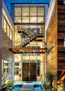 Modern building exterior with large windows and a visible staircase, showcasing a completed project by Plumb Partners LLC in Miami, FL.
