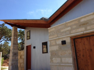 Close-up of a modern building exterior featuring stone and corrugated metal siding by Enertech Builders in Austin, TX.