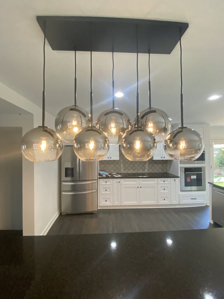 A modern chandelier installed over a kitchen island by Infinite Creations Construction, LLC in Denver, CO