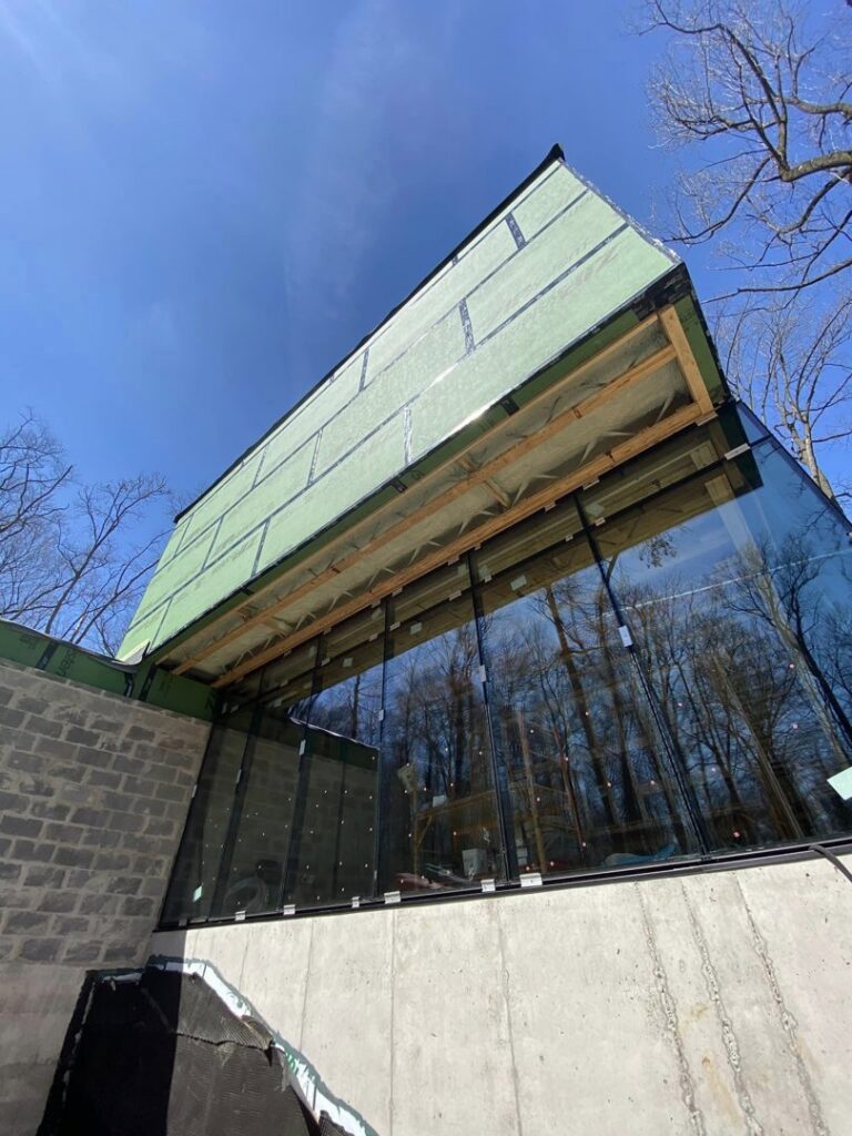 The exterior of a modern commercial building under construction with large glass windows, showcasing general contractor expertise by Olympus Spray Foam in Philadelphia, PA.