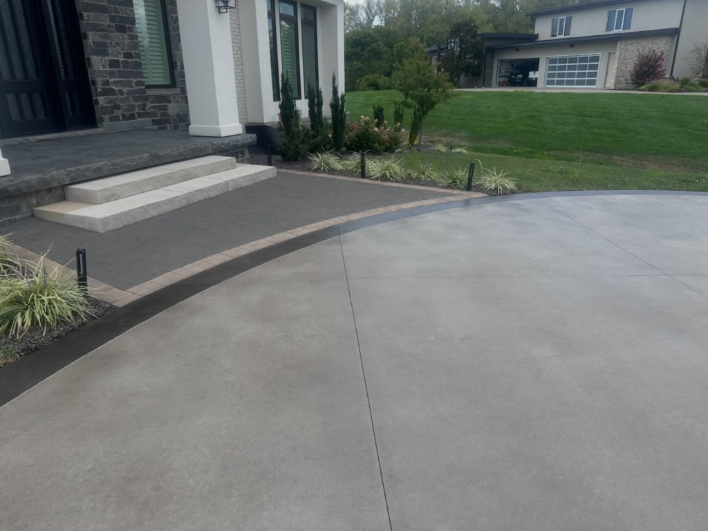 A sleek, modern concrete driveway and walkway leading to a home, coated by 812 Concrete Coatings in Evansville, IN.