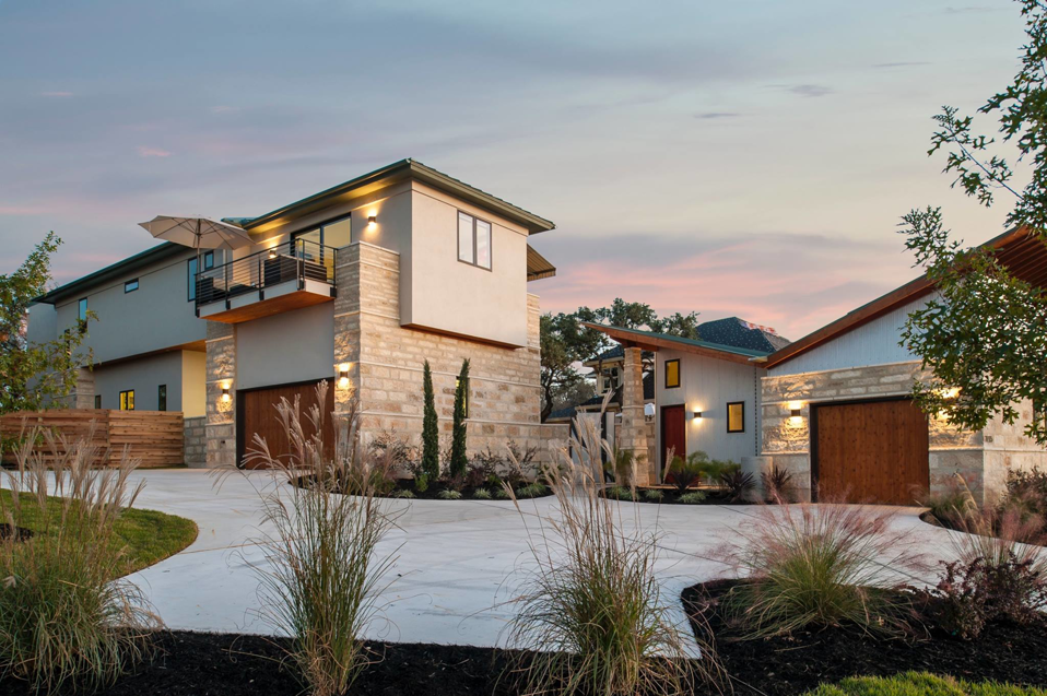 A stunning modern custom home exterior with a concrete driveway built by Enertech Builders in Austin, TX.