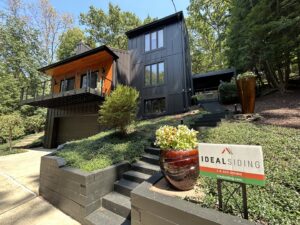 A modern dark house with stylish wood accents, showcasing a completed exterior renovation by Ideal Siding Richmond, VA.