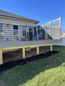 A modern deck with horizontal railings and a decorative privacy screen by Chad Fry the Deck Guy LLC in Blue Springs, MO.
