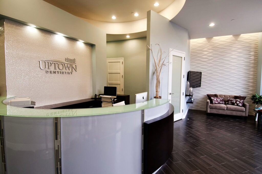 A modern and inviting dental office reception area with a curved desk and textured wall, completed by Siegel Construction in Eugene, OR.