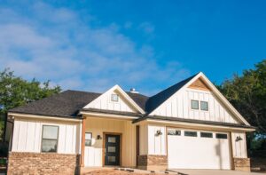 The exterior of a modern farmhouse style custom home with white siding and brick accents by Aubrey Homes in Austin, TX