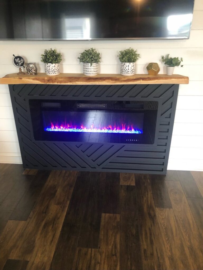 A modern fireplace with a geometric surround, wooden mantel, and mounted TV installed by The Huckleberry Handyman in Meridian, ID.
