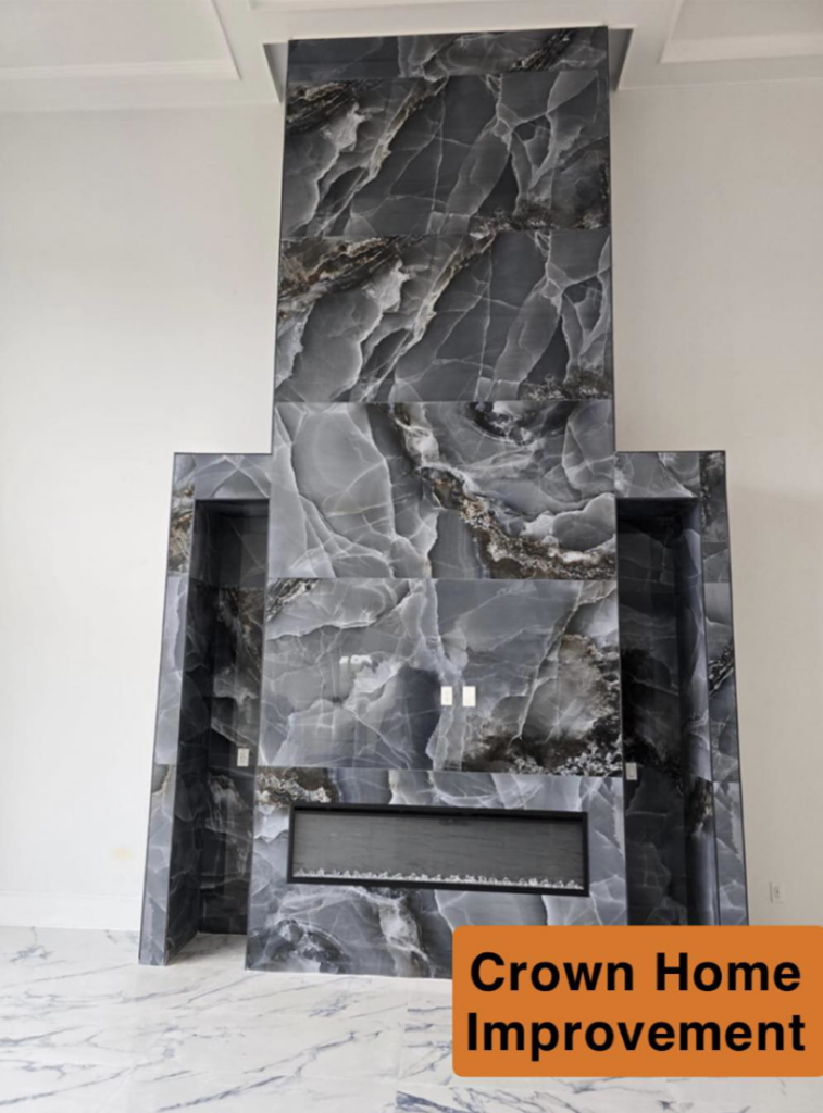 A newly installed modern fireplace with dark marble-like tile surround by Crown Home Improvements in Charlotte, NC