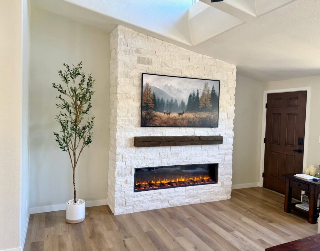 A modern living room featuring a stacked stone fireplace with a wooden mantel and integrated TV mount by Midwest Home Remodeling & Design LLC in Chicago, IL.