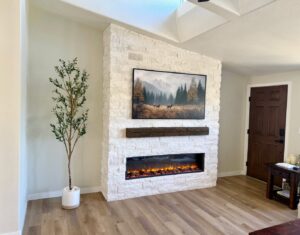 A modern living room featuring a stacked stone fireplace with a wooden mantel and integrated TV mount by Midwest Home Remodeling & Design LLC in Chicago, IL.