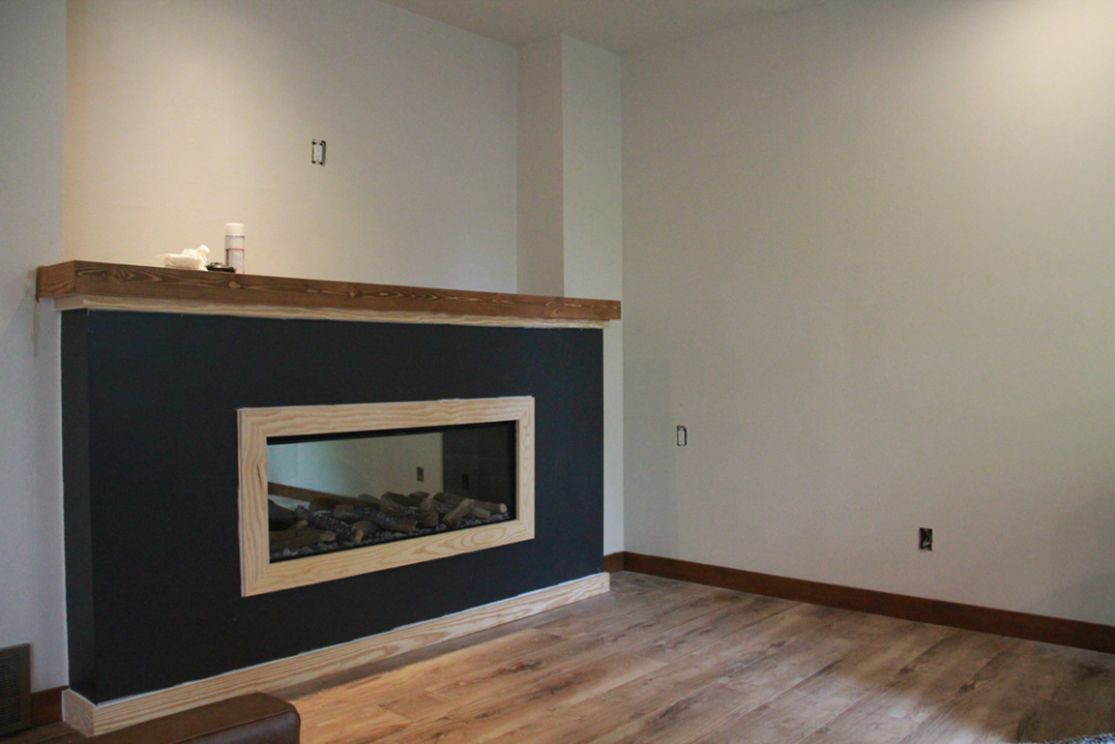 A modern fireplace surround with a dark finish and wooden mantel, installed by RT Handyman LLC in Sioux Falls, SD.