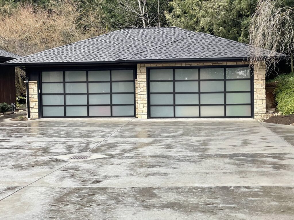 A modern garage with frosted glass panel doors and stone accents by Garages Etc in Tacoma, WA