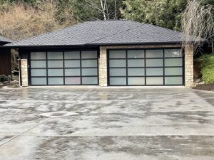 A modern garage with frosted glass panel doors and stone accents by Garages Etc in Tacoma, WA