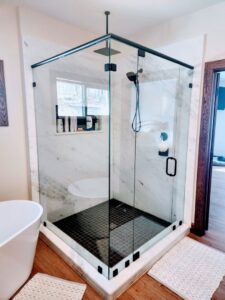 Modern glass shower enclosure with marble walls and black tile floor installed by J and R Granite Industry in Columbus, OH.