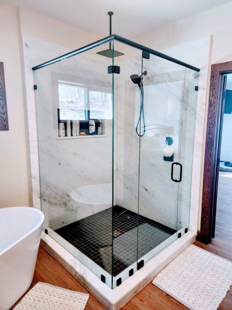 Modern glass shower enclosure with marble walls and black tile floor installed by J and R Granite Industry in Columbus, OH.