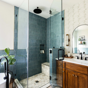 A modern glass shower enclosure with blue-green tiles and a built-in bench by Rockin' Remodeling LLC in Austin, TX
