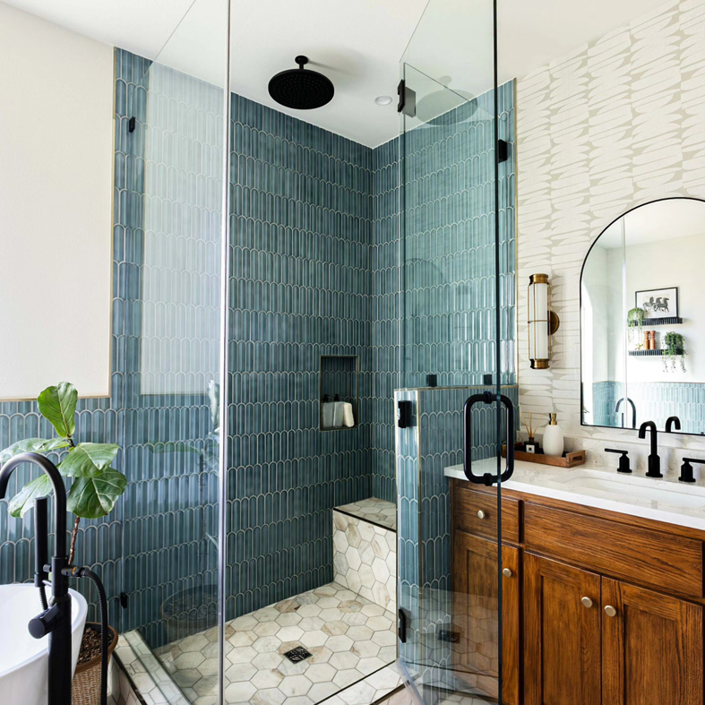A modern glass shower enclosure with blue-green tiles and a built-in bench by Rockin' Remodeling LLC in Austin, TX