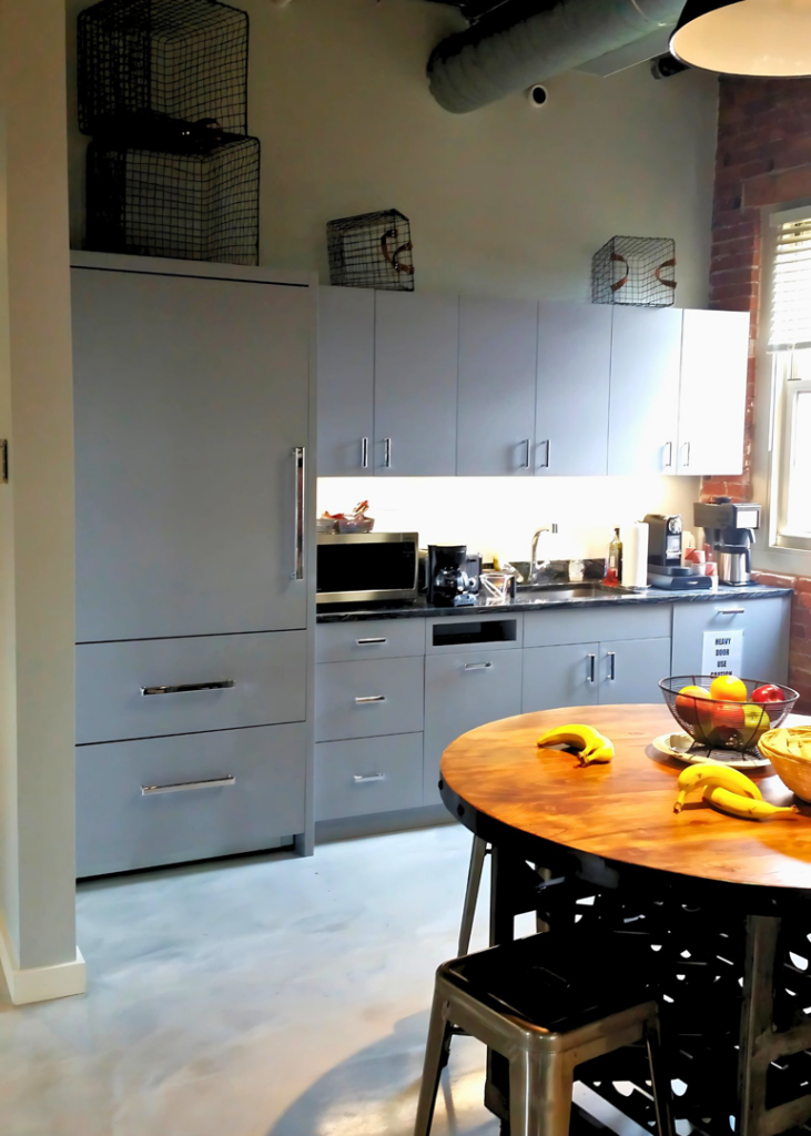 A modern gray kitchen and breakroom with new cabinets and refrigerator installed by J. Forrest Development, LLC in Matthews, NC.