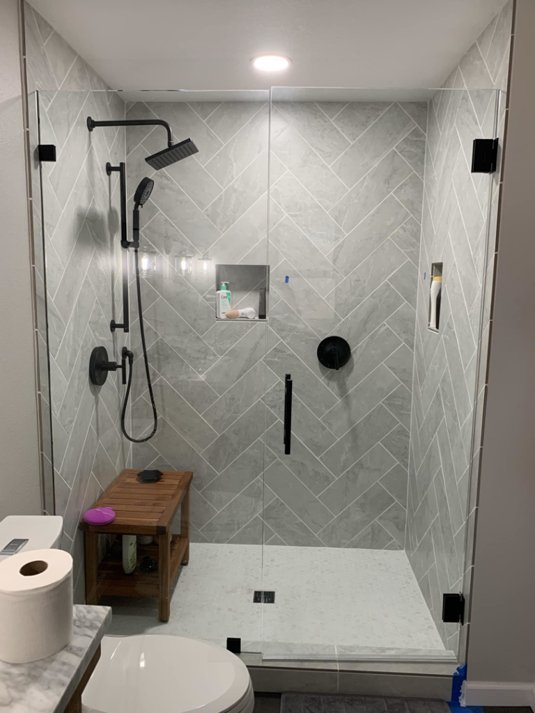 A modern shower with grey herringbone tiles and black fixtures installed by Andalex Construction LLC in Gresham, OR.