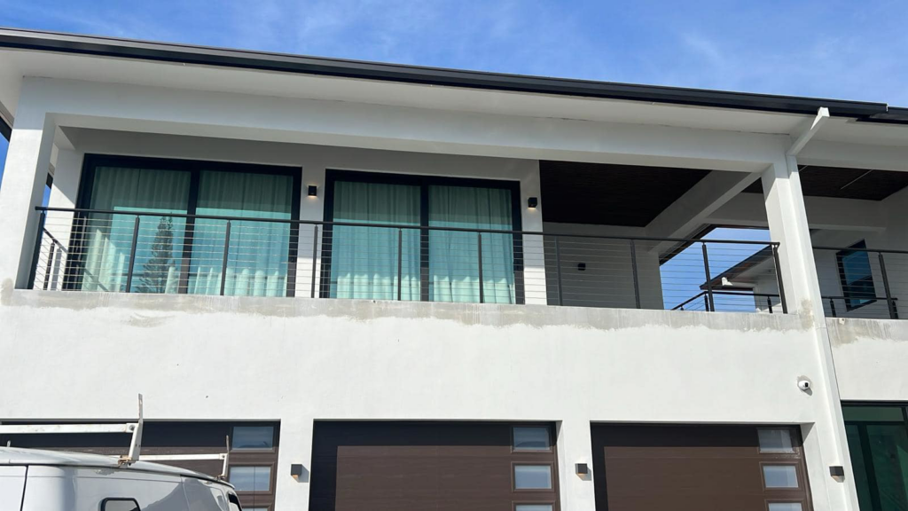 Modern home with balcony and garage doors, showcasing general contractor work by American Glass & Window Inc in Hialeah, FL.