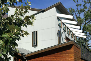 A modern home exterior featuring unique siding, multiple windows, and architectural sunshades by Kaleidoscope Design Build in Houston, TX.