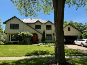 A modern home featuring a distinctive metal roof and light-colored siding, completed by First Contracting Group in Rockford, IL.
