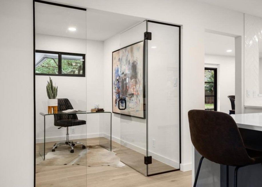 A modern home office featuring glass walls and door, with a sleek desk and chair by Proper 3 Renovations in Austin, TX