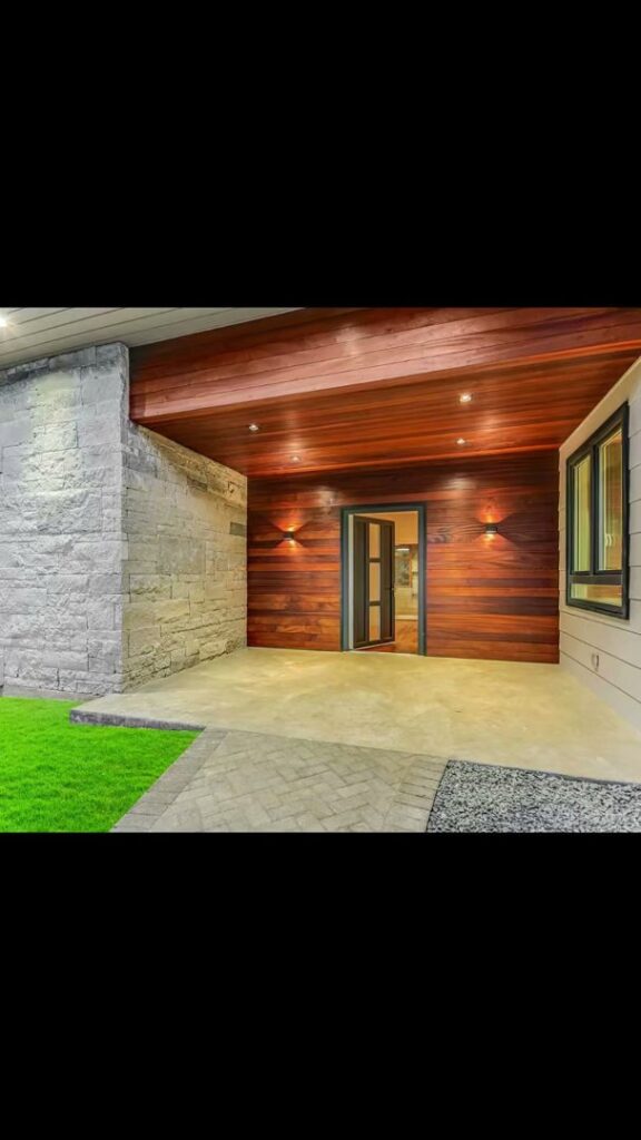 A contemporary house entrance featuring stone and wood paneling by Transformations Custom Build in Austin, TX