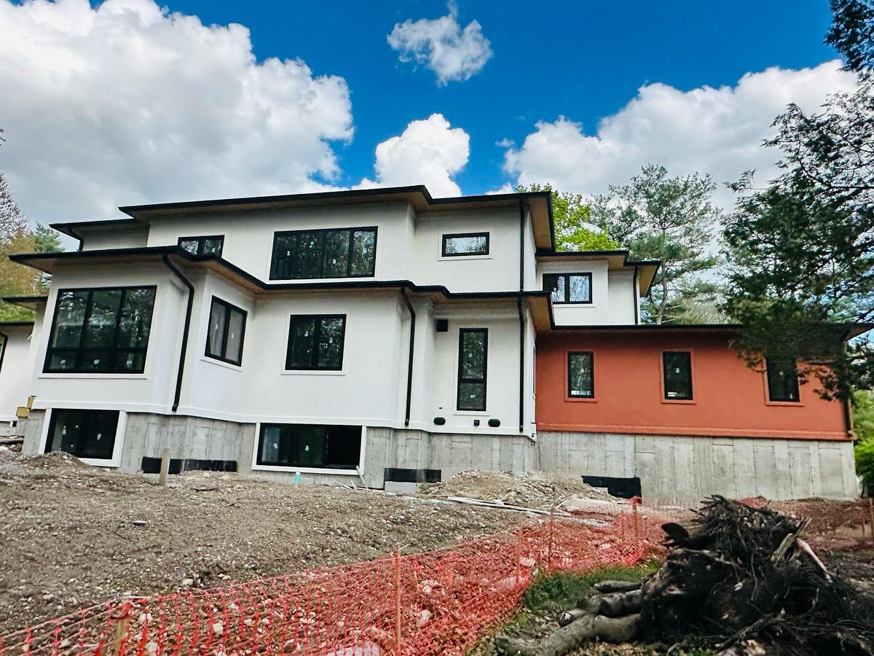 A modern house under construction featuring white and orange stucco or EIFS exterior finishes by WS Design Eifs-Stucco in Boston, MA.