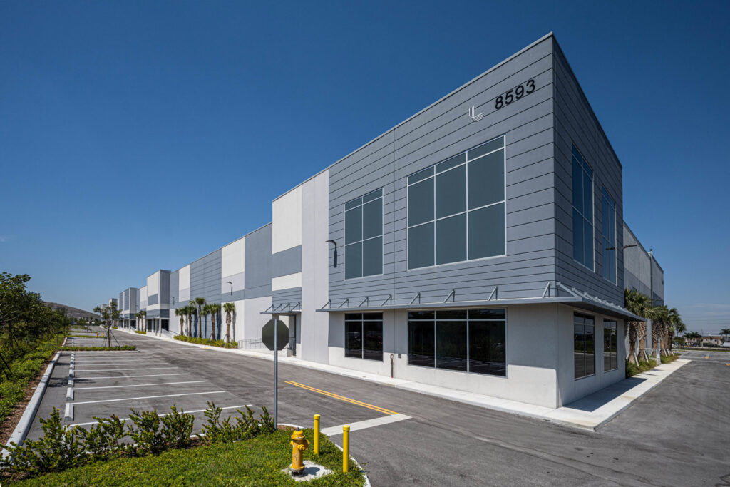 Exterior of a modern industrial building with a large parking lot, completed by Hernandez Construction & Development in Fort Lauderdale, FL.