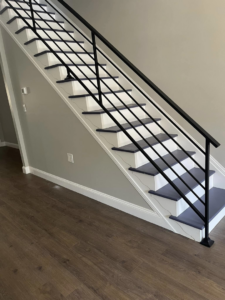 A modern interior staircase featuring black iron railings and dark steps by AC Fence and Ironworks in Philadelphia, PA.