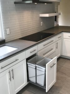 A modern kitchen remodel with grey subway tile backsplash, dark countertops, and white cabinets by Home Platinum Services, LLC in Plano, TX