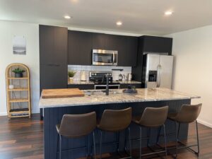 A sleek modern kitchen featuring black cabinets, stainless steel appliances, and a granite island by Pioneer Built in St. Petersburg, FL.