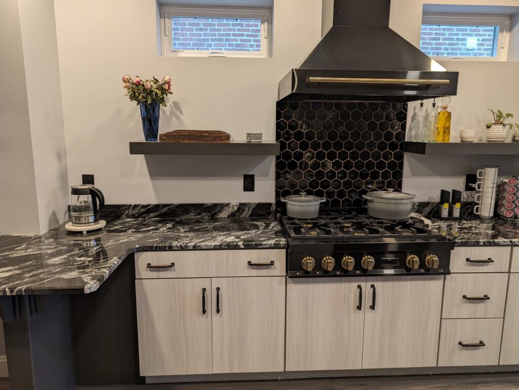 A modern kitchen with a black hexagonal backsplash and marble countertops by Shafer Construction, LLC in Bethlehem, PA.