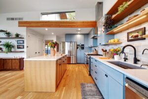 A stylish modern kitchen with light blue cabinets, a wooden island, and open shelving by Transformations Custom Build in Austin, TX